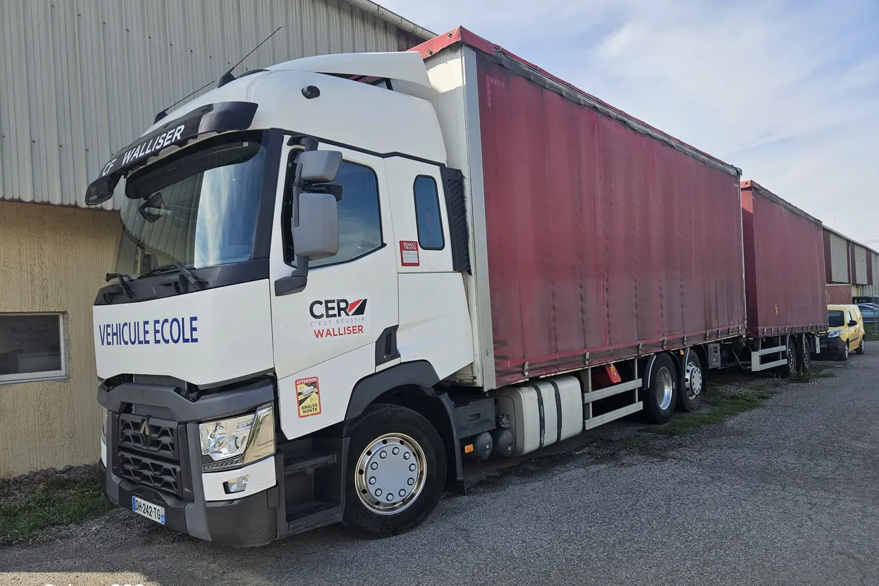 Le camion-ecole et sa remorque stationnes le long du hangar du centre.